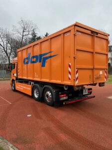 Ein großer Müllcontainer wird angeliefert.